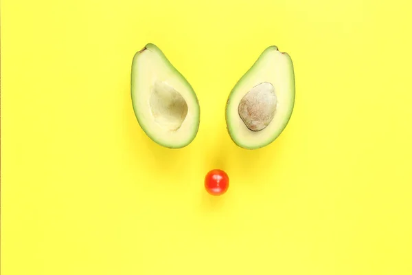 Concept végétarien créatif smilling : deux moitiés d'avocat avec et sans graines et tomate sur fond jaune. — Photo