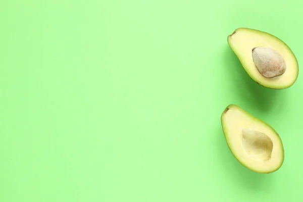 Deux moitiés d'avocat avec et sans graines sur fond vert. Vue du dessus. — Photo