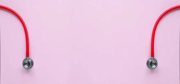Pembe arka planda kırmızı stetoskobun üst görüntüsü. Tıp konsepti. Sancak Boyutu.