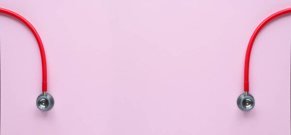 Top view of red stetoscope on pink background. Medicine concept. Banner Size.