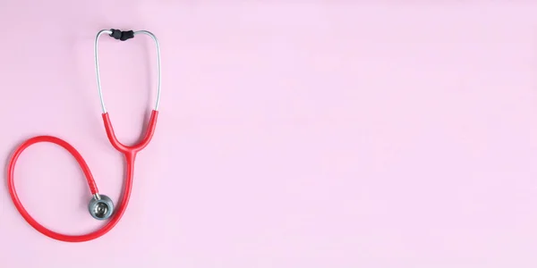 Pembe arka planda kırmızı stetoskobun üst görüntüsü. Tıp konsepti. Sancak Boyutu.