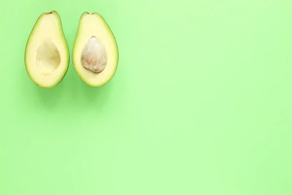 Deux moitiés d'avocat avec et sans graines sur fond vert. Vue du dessus. — Photo