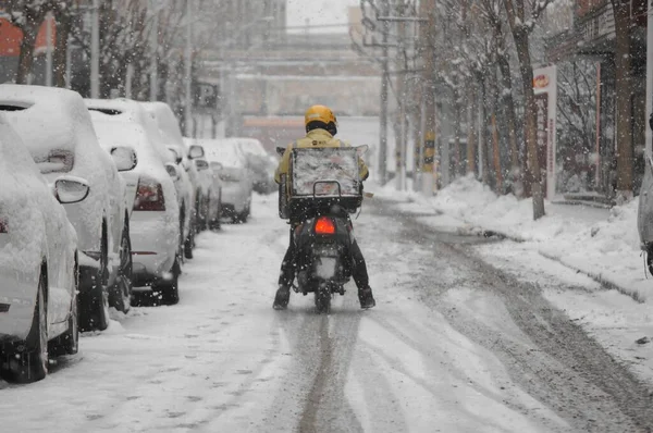 winter snowstorm, snow-covered cars, a car, a motorcycle, a snowmobile, a city street