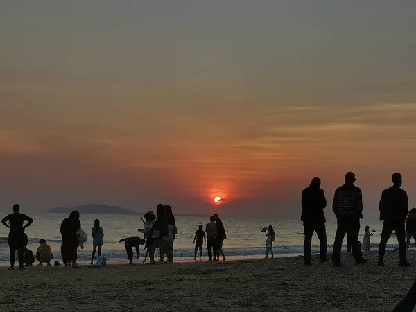 silhouette of a group of people walking on the beach at sunset