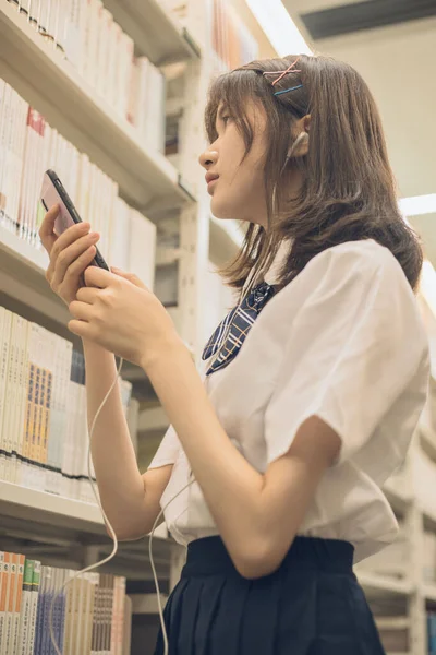 young woman using mobile phone in library