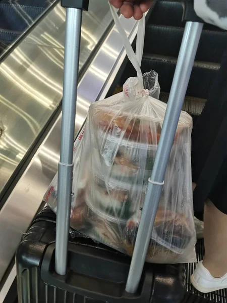a man in a white coat is holding a tray with a bag of meat in the store