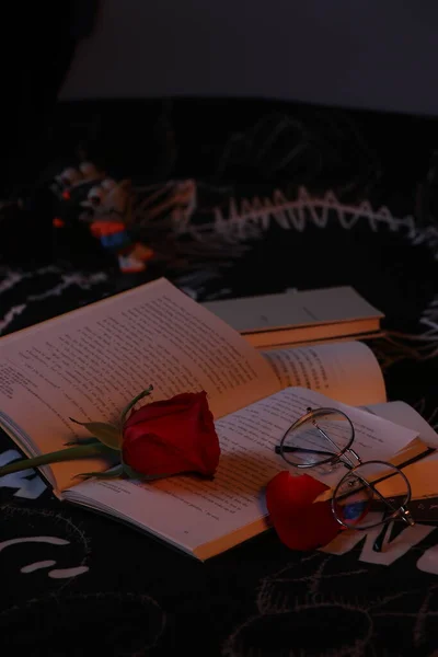 a book with a candle and a red rose on a black background