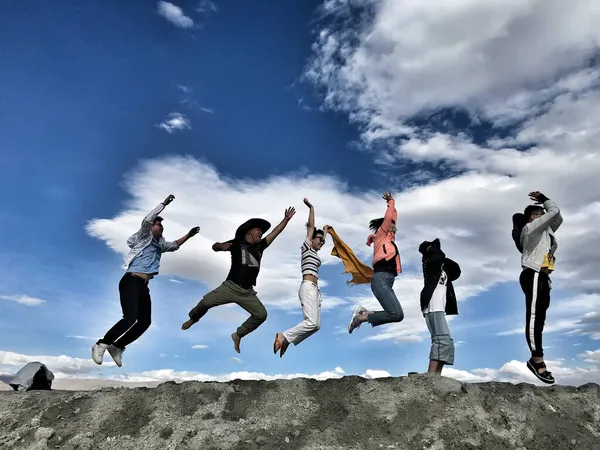 group of happy young people jumping in the sky