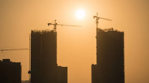 construction cranes and building under the sun