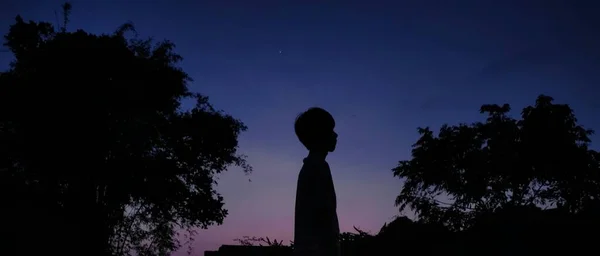 silhouette of a man in a dress on the background of the moon