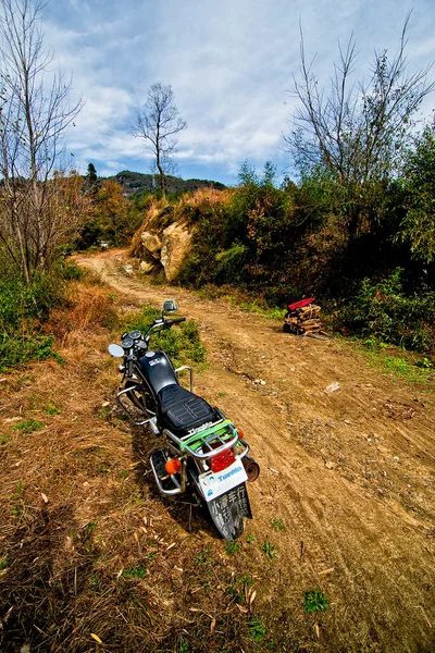 a small motorcycle parked on the road in the forest