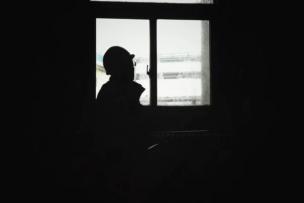 silhouette of a man in a black dress with a window