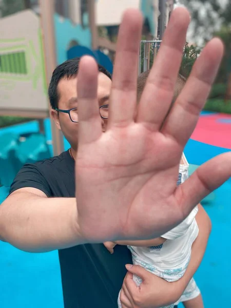 a man in a blue shirt and a white t-shirts are raised and a hand on the background