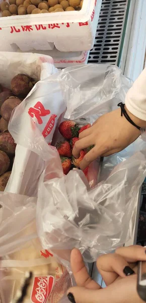 woman in a white gloves holds a bag of wine in a plastic box