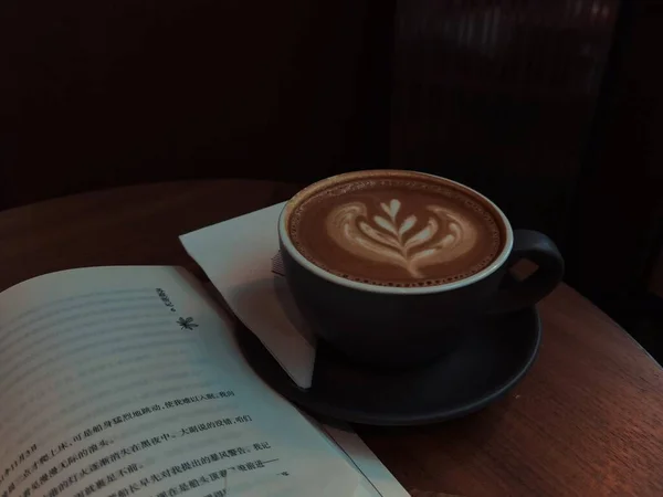 cup of coffee and a book on a wooden table