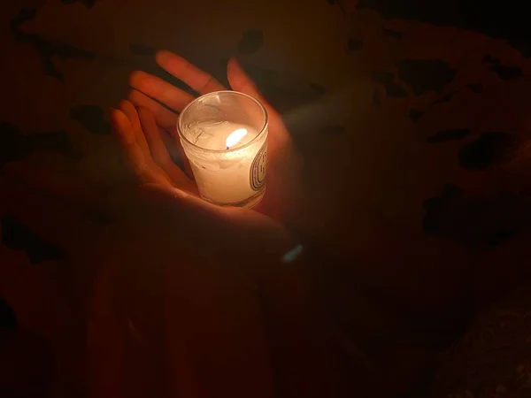 candle in the hands of a woman in a glass