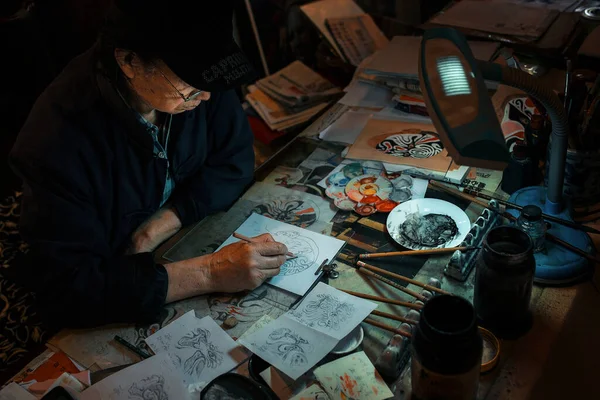 old man in a leather jacket and a tattoo with a pencil