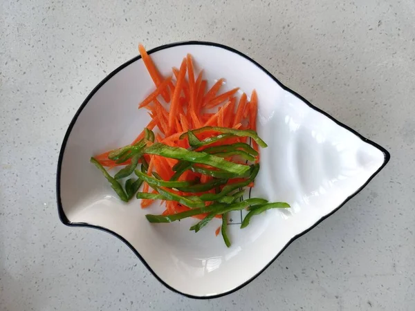 salad with red pepper and green leaves on a white plate