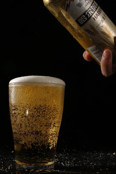 beer glass with foam and a cup of coffee on a black background