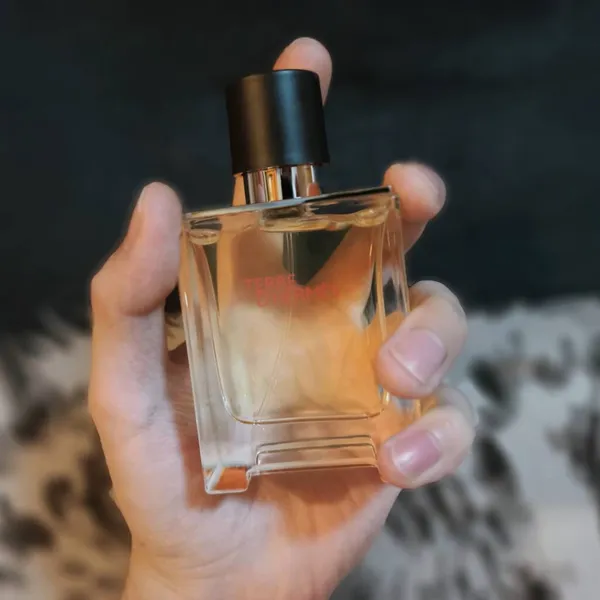 female hand with perfume bottle on a dark background