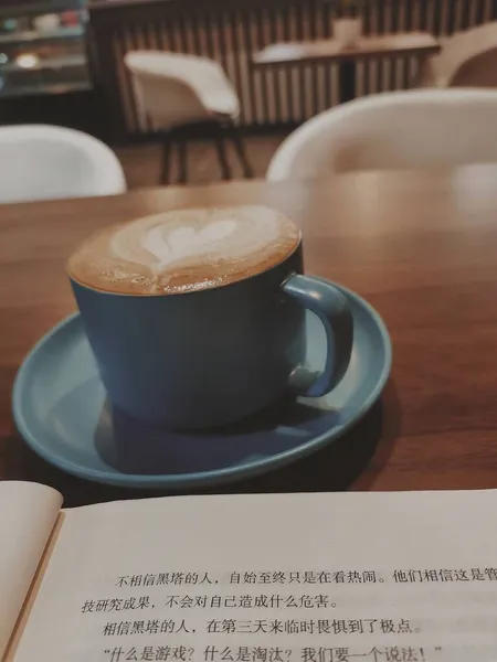 cup of coffee and a book on a wooden table