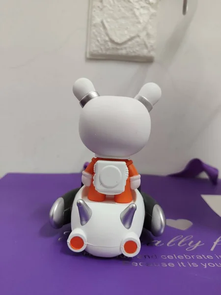 a miniature robot with a toy doll on a white background