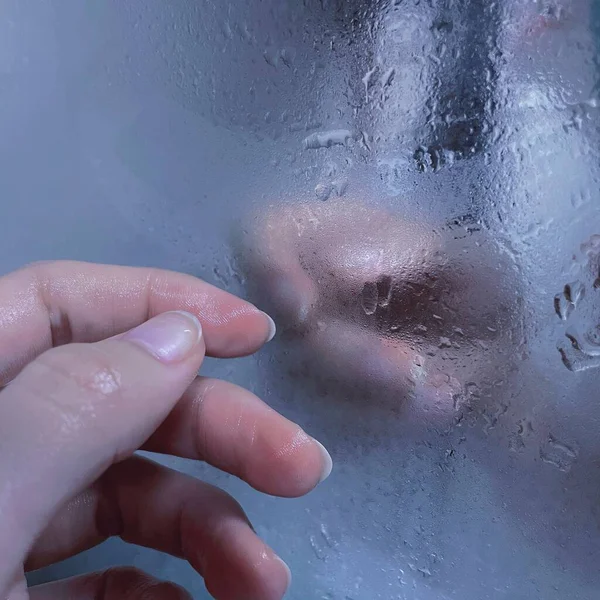 woman washing her face with water drops on the glass