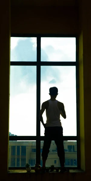 silhouette of a man in a white shirt and a black dress on the background of the window