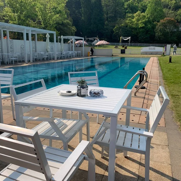 outdoor swimming pool with green grass and wooden deck chairs