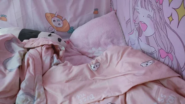 sleeping baby bed with pink and purple pillows on the floor