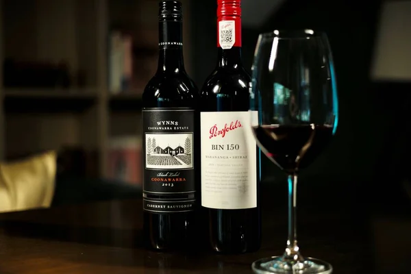 red wine bottle and glass of white and black bottles of different sizes and shapes on a wooden table