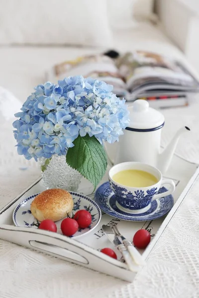 breakfast with a cup of tea and flowers on a white wooden background