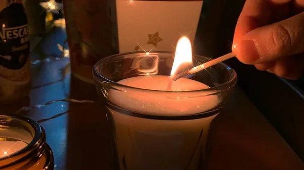 candle in the hands of a woman in a dark room