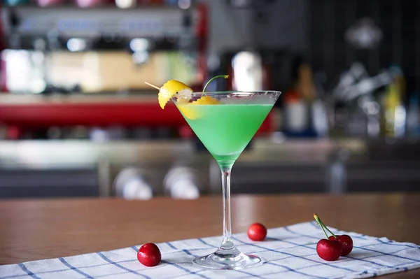 cocktail with red and green olives on bar counter