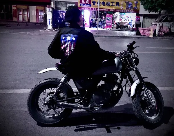 a man in a black dress with a motorcycle on the street