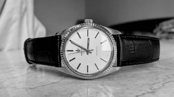 black and white photo of a silver watch on a wooden background