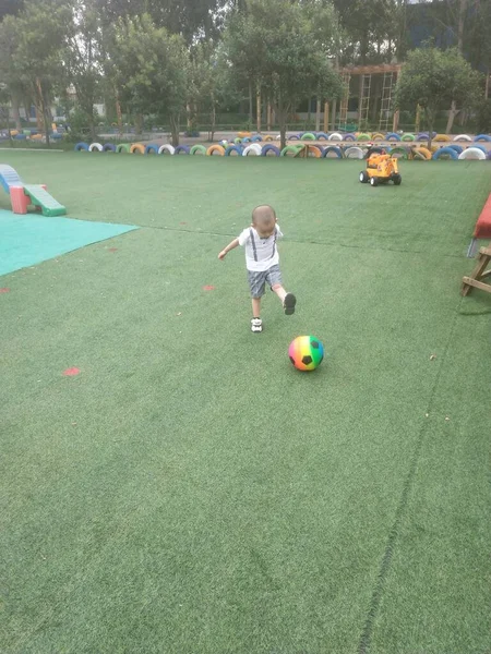 little boy playing with ball in the park