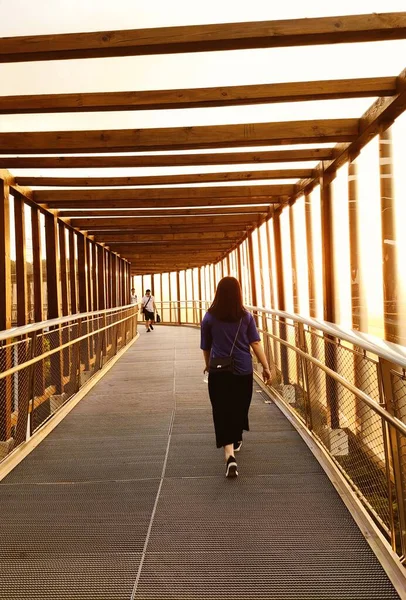 woman in a black dress walking on the bridge