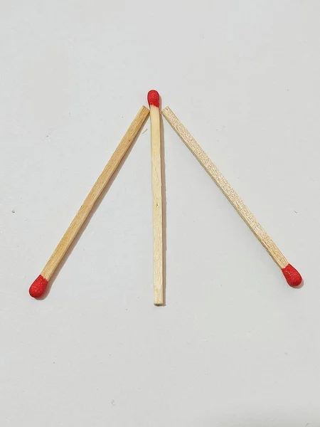 a wooden sticks with a red pencil on a white background