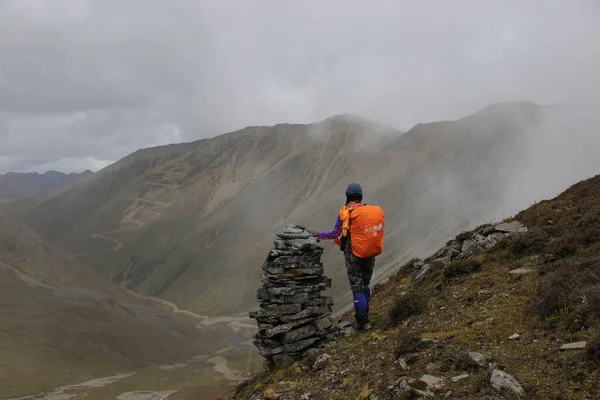 man in a jacket with a backpack on the top of the mountain