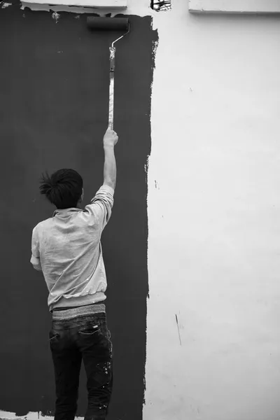young man painting wall with paint roller