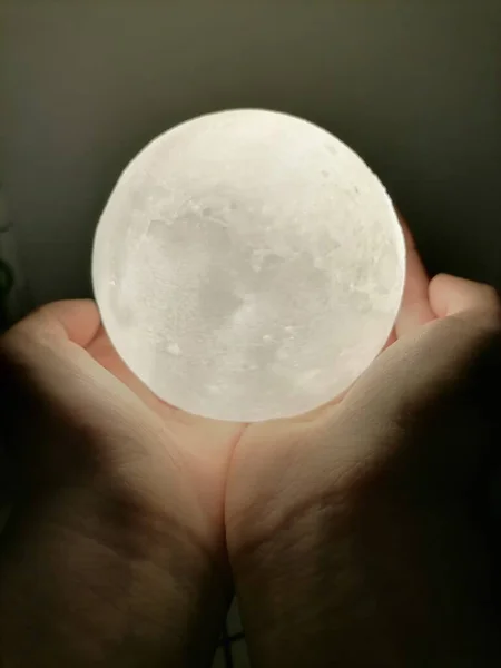 white moon in the hands of a woman\'s hand