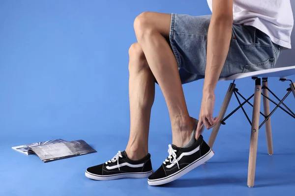 cropped view of woman holding shoes with legs on color background