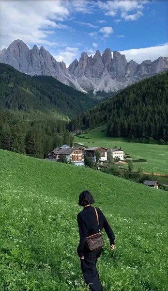 a man in a green jacket and a backpack on a mountain slope