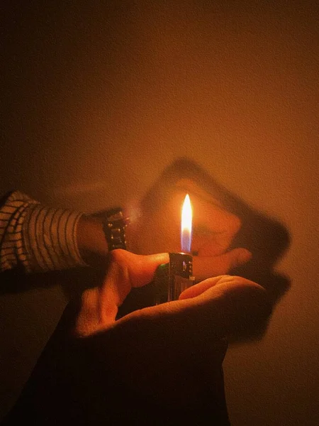 burning candle in the hands of a woman