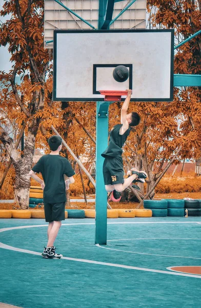 group of young people playing basketball outdoors