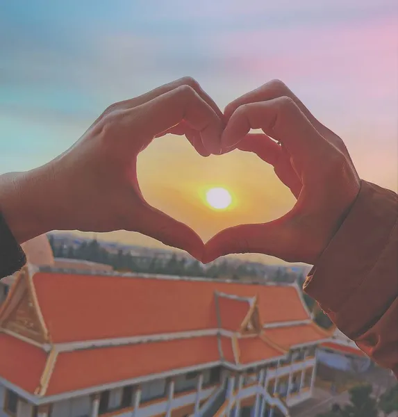 heart shape in hand on the background of the sunset