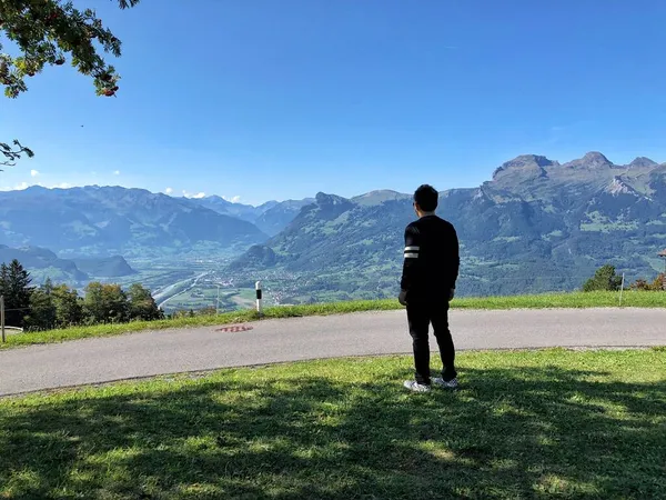 a man in a green jacket and a backpack on the background of the mountains