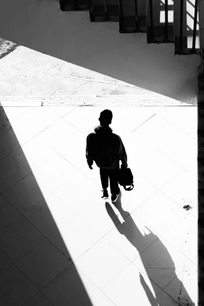 silhouette of a man in a black suit and a white shirt walking on the street