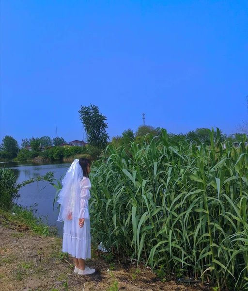 the girl in the green dress with a bag of rice in the background of the water